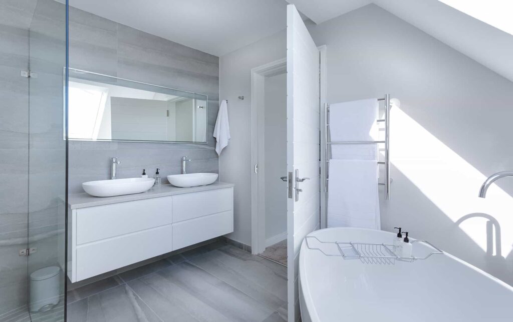 Salle de bain blanche et lumineuse avec deux lavabos blancs.