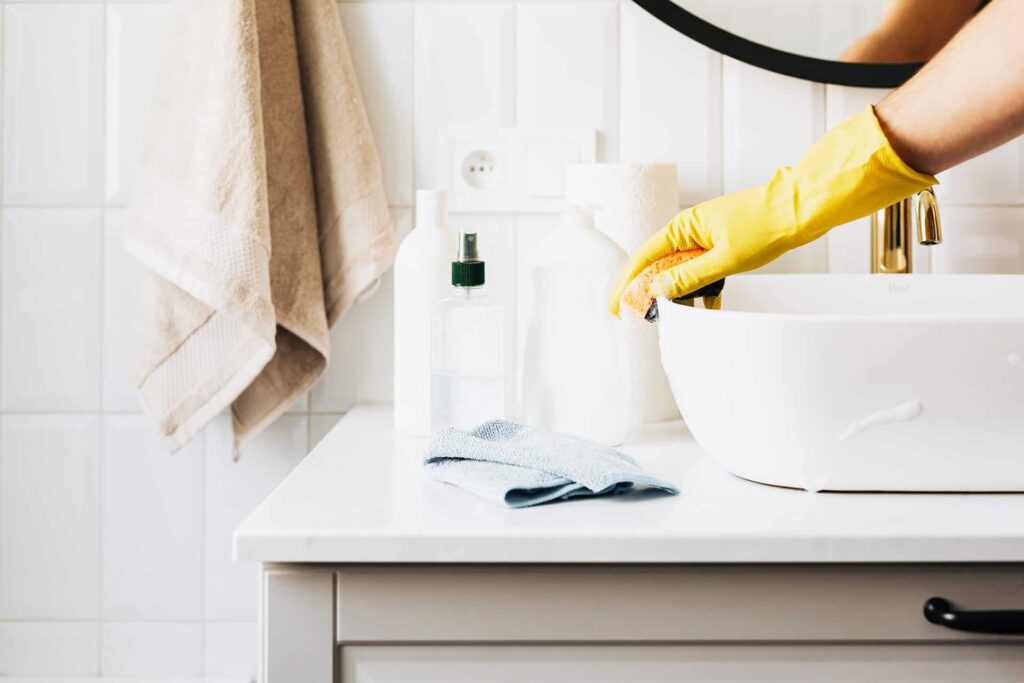 Femme nettoyant en profondeur un lavabo avec des produits de nettoyage.