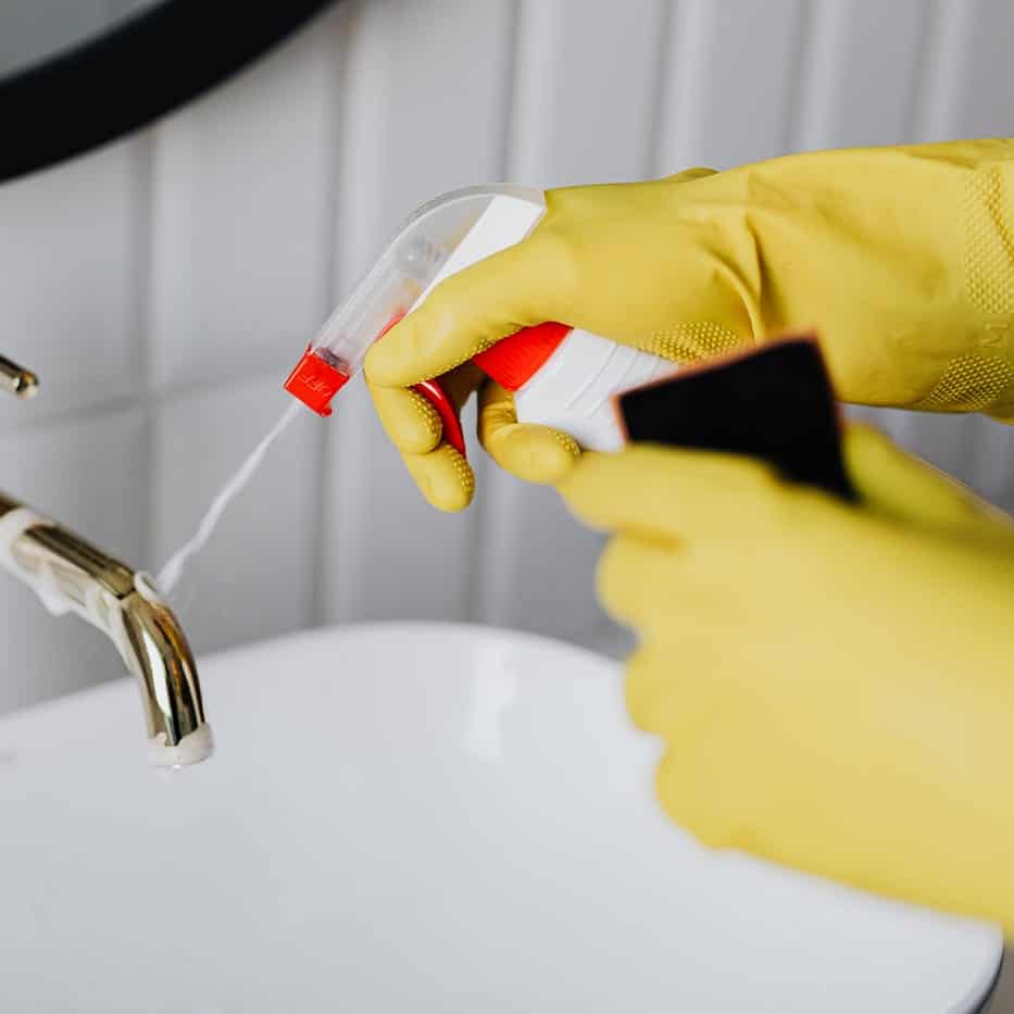 emme nettoie un lavabo à l'aide de produits écologiques et respectueux de l'environnement.