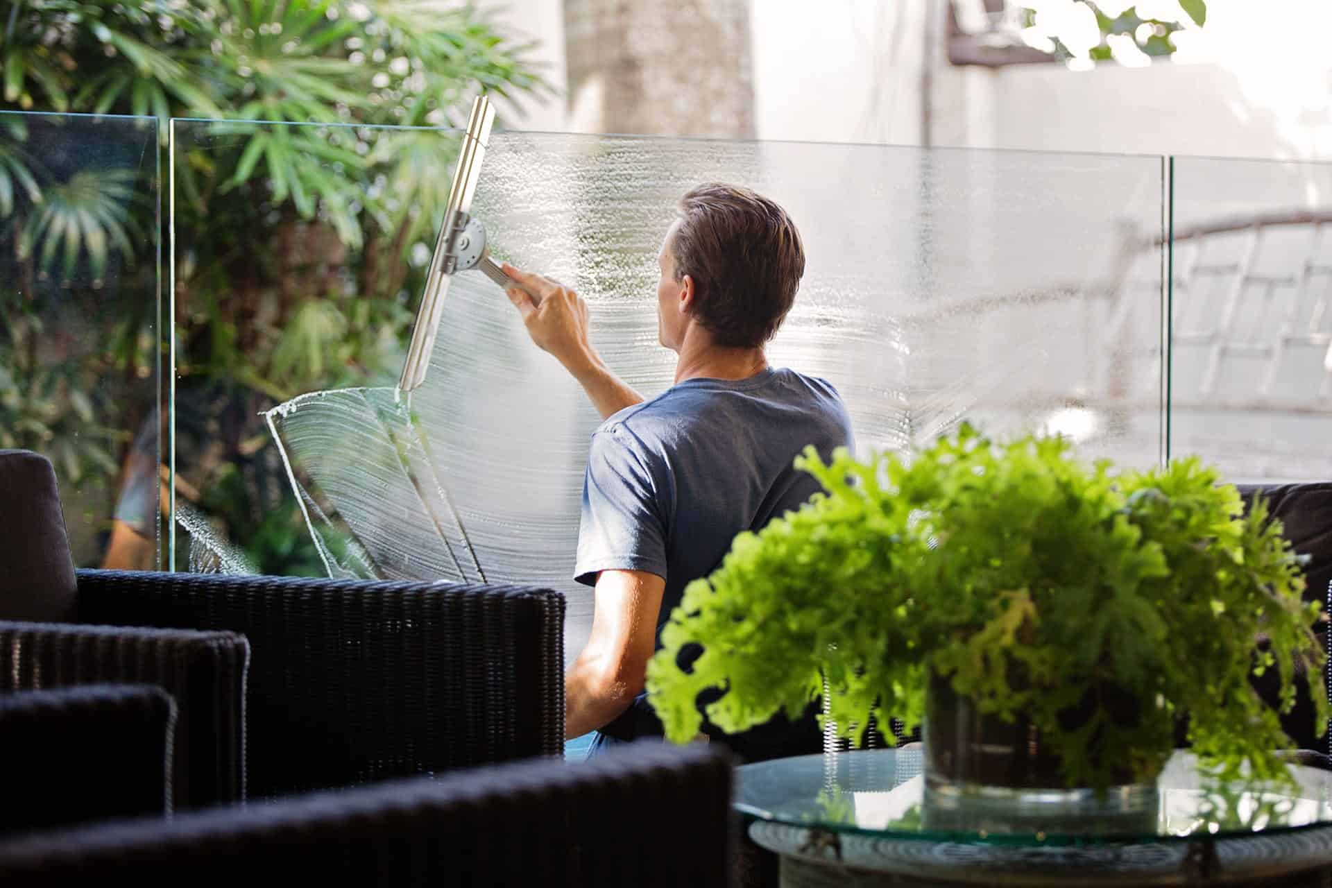 Homme nettoyant le miroir extérieur d'un restaurant.