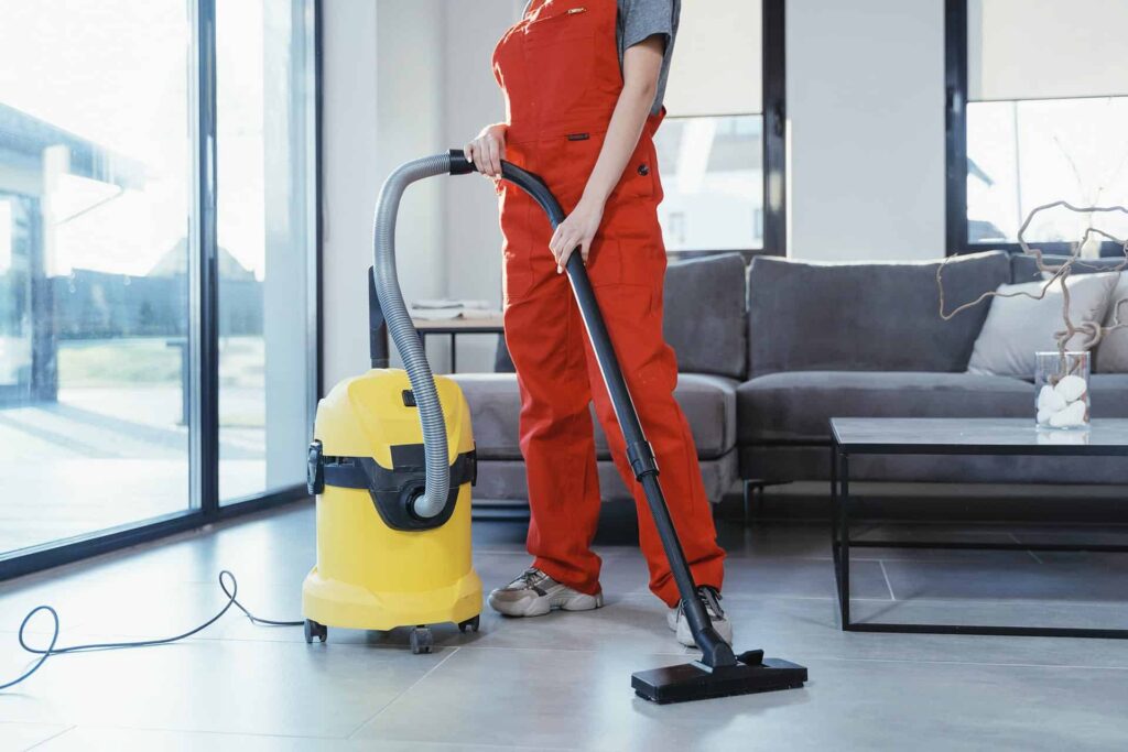 Femme nettoyant le sol avec un aspirateur.